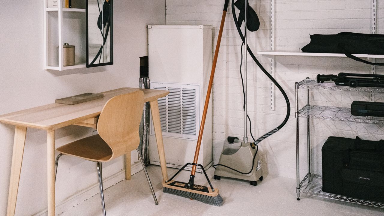 services-04 A tidy home office space featuring a wooden desk, chair, broom, and cleaning equipment.